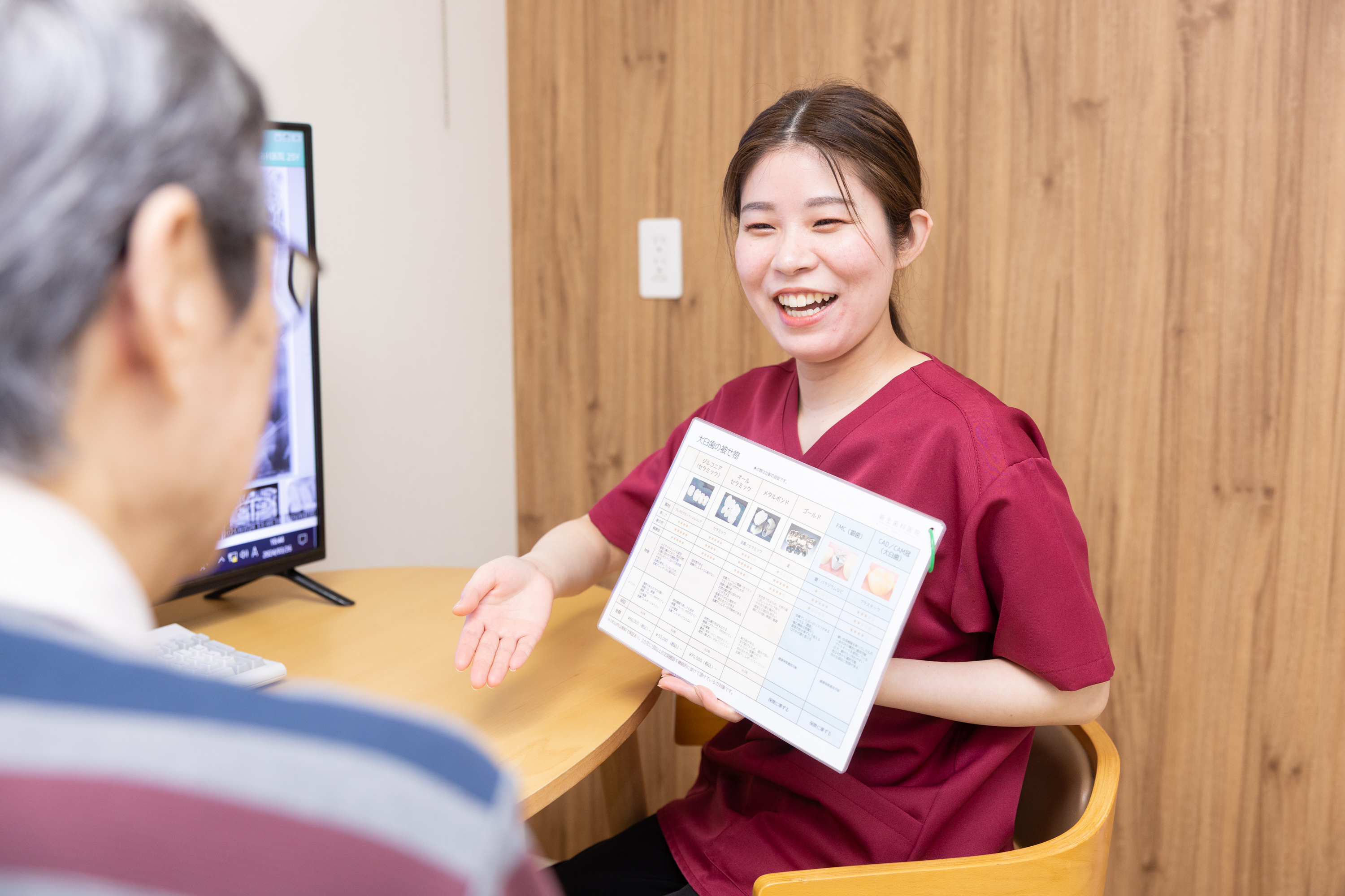 新生歯科医院のスタッフが患者さんに笑顔で治療内容を説明している様子